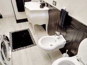 A bathroom with a white sink, a bidet, a toilet, and a washing machine.
