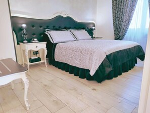 A bedroom with a bed, nightstands, a desk, and a window with curtains.
