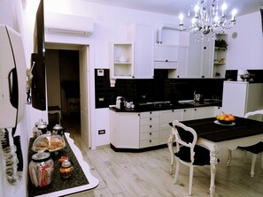 A modern kitchen with white cabinetry, a black countertop, and a chandelier.