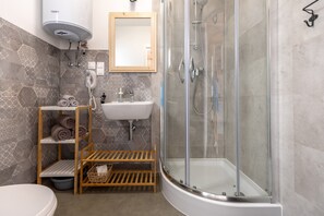 A bathroom with a glass-enclosed shower, a white sink, a towel rack, and a heater. - Comfortable holiday homes with SPA Rewal (Rewal)