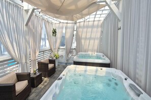 A spa area with two hot tubs, wicker furniture, and a view of the city. - Comfortable holiday homes with SPA Rewal (Rewal)
