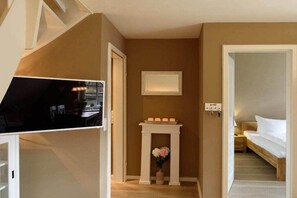 A hotel room with a bed, a bedside table, a small table with candles, and a vase with flowers. - Holiday apartment in Wyk with swimming pool (Wyk)
