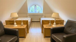 Ein Zimmer mit zwei Betten, einem Fenster, einer Heizung und zwei Lampen.