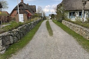 Un camino rural bordeado por muros de piedra y casas tradicionales con tejados de paja.
