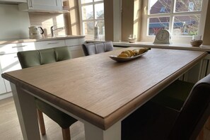 A kitchen with a central island, a kettle, a clock, and a bowl of lemons on the windowsill. - Holiday apartment in Wyk with swimming pool (Wyk)