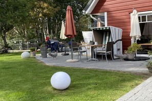 Un área de patio al aire libre con una mesa de comedor, sillas y sombrillas.