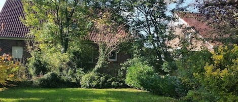 A residential area with a brick house, a well-maintained lawn, and mature trees.