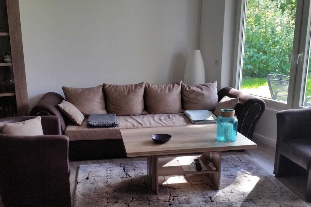 A cozy living area with a sofa, a coffee table, and a window with a view of greenery.