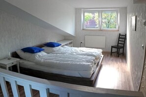 A bedroom with a bed, a window, a chair, and a radiator. - Holiday home in Hooksiel with swimming pool (Hooksiel)