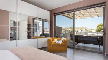 A modern bedroom with a large bed, a sofa, a wardrobe, and a sliding glass door leading to a balcony.
