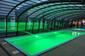 A swimming pool with a glass enclosure and a green-lit interior. - Comfortable holiday homes with SPA Rewal (Rewal)