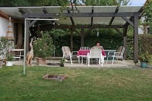 A covered patio with a table and chairs, surrounded by potted plants and a fire pit. - Holiday apartment with 1 bedroom (Edertal Kleinern)