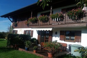 A two-story building with a balcony, potted plants, and a small outdoor seating area. - Holiday apartment Havel (Hofheim Gemeinde Spatzenhausen)