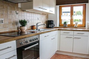Une cuisine équipée d’une cuisinière, d’un four, d’un évier et de placards.