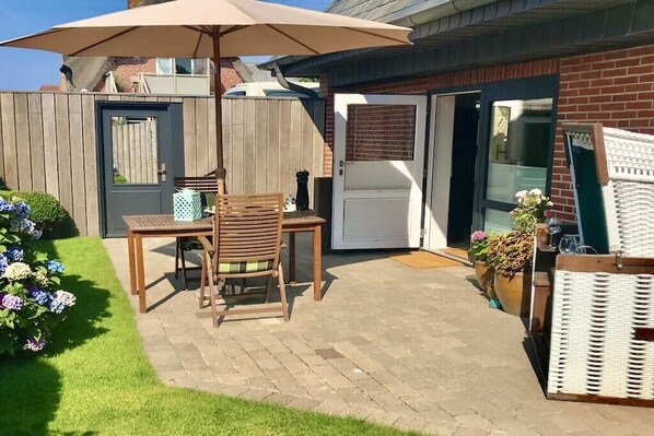 Un patio con una mesa, sillas, una valla de madera y una puerta que da a un garaje.
