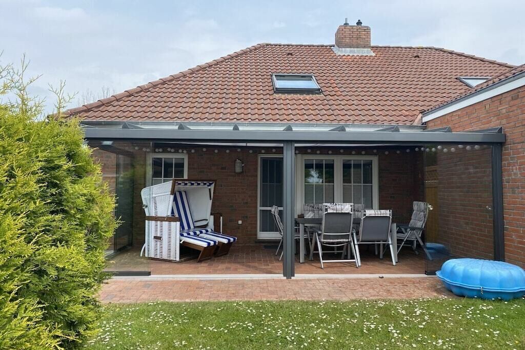 Une terrasse couverte avec des meubles d’extérieur, une maison en briques et un ciel dégagé.