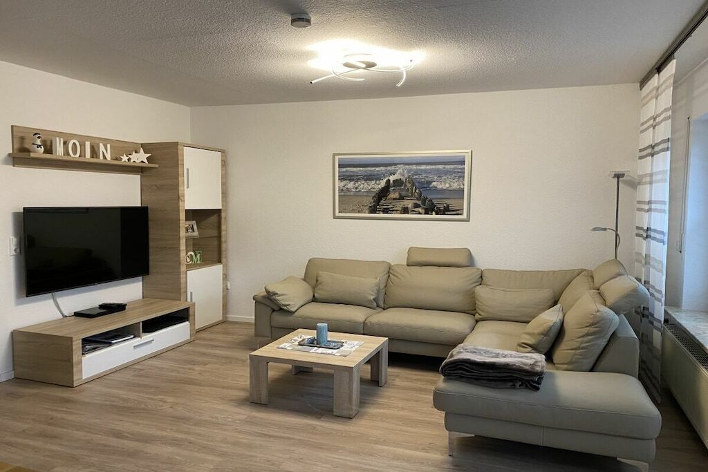 A modern living room with a flat-screen TV, a beige sofa, a coffee table, and a framed picture on the wall.