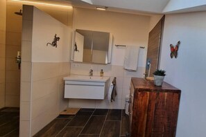 Een moderne badkamer met een wastafel, spiegel en douchehoek.
