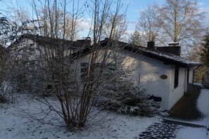 Une maison recouverte de neige, avec un petit porche et un chemin menant à l’entrée.