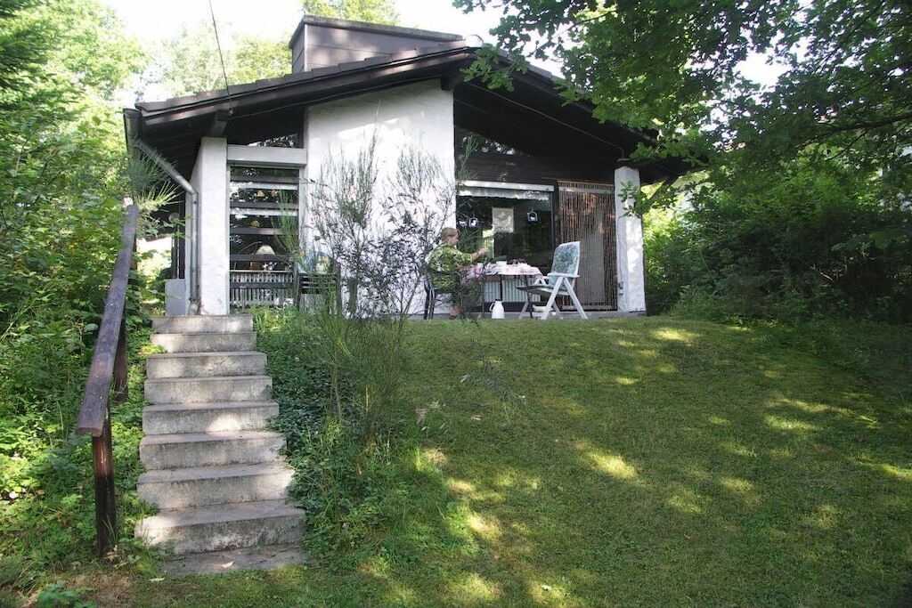 A house with a covered porch, a set of concrete stairs, and a grassy yard.
