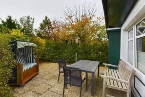 An outdoor patio with a wooden bench, a table, and a covered seating area. - Holiday apartment Palladium 1 (Langeoog)