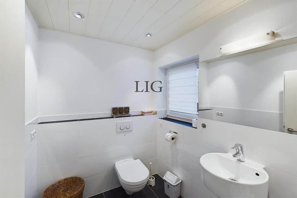 Een kleine badkamer met toilet, wastafel en een klein raam.