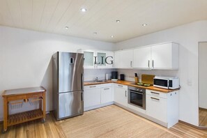 Une cuisine moderne avec des meubles blancs, des appareils en acier inoxydable et un plan de travail en bois.