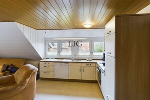A compact kitchen with a built-in dishwasher, a sink, and a window above it. - Holiday apartment Palladium 2 (Langeoog)