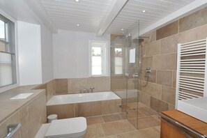 Un baño moderno con bañera, inodoro y zona de ducha.