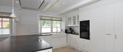 Una cocina moderna con armarios blancos, encimera negra y horno integrado.