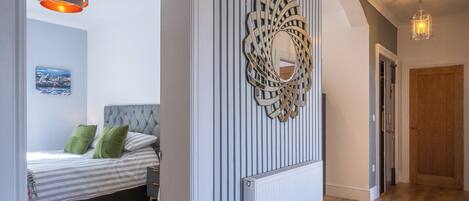 A hallway with a wooden floor, a radiator, and a decorative wall piece.