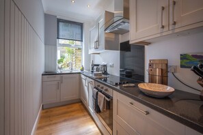 A compact kitchen with a window, built-in oven, and modern appliances. - Cosy former converted bank in heart of a busy working fishing village. (Mallaig)