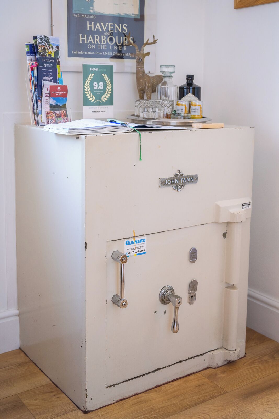 A white metal safe with a 'John Tann' label, a 'Gunnebo' sign, and a 'Hotel Social' award on top.