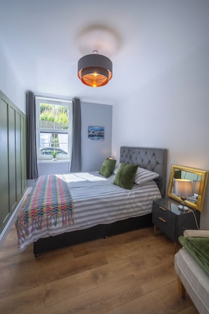 A bedroom with a bed, bedside table, lamp, and a window with curtains.