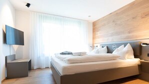 Ein modernes Schlafzimmer mit einem Bett, einem Flachbildfernseher und einer Wand mit Holzvertäfelung.