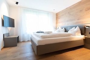 Un dormitorio moderno con cama, televisor de pantalla plana y una pared de acento de madera.