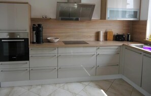 A modern kitchen with a built-in oven, a coffee machine, and a microwave. - Apartment with Fireplace, Private Garden, and Wi-Fi (Milmersdorf)