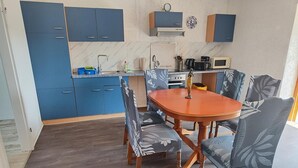 Une cuisine de taille réduite avec des meubles bleus, une table à manger en bois et des chaises assorties.