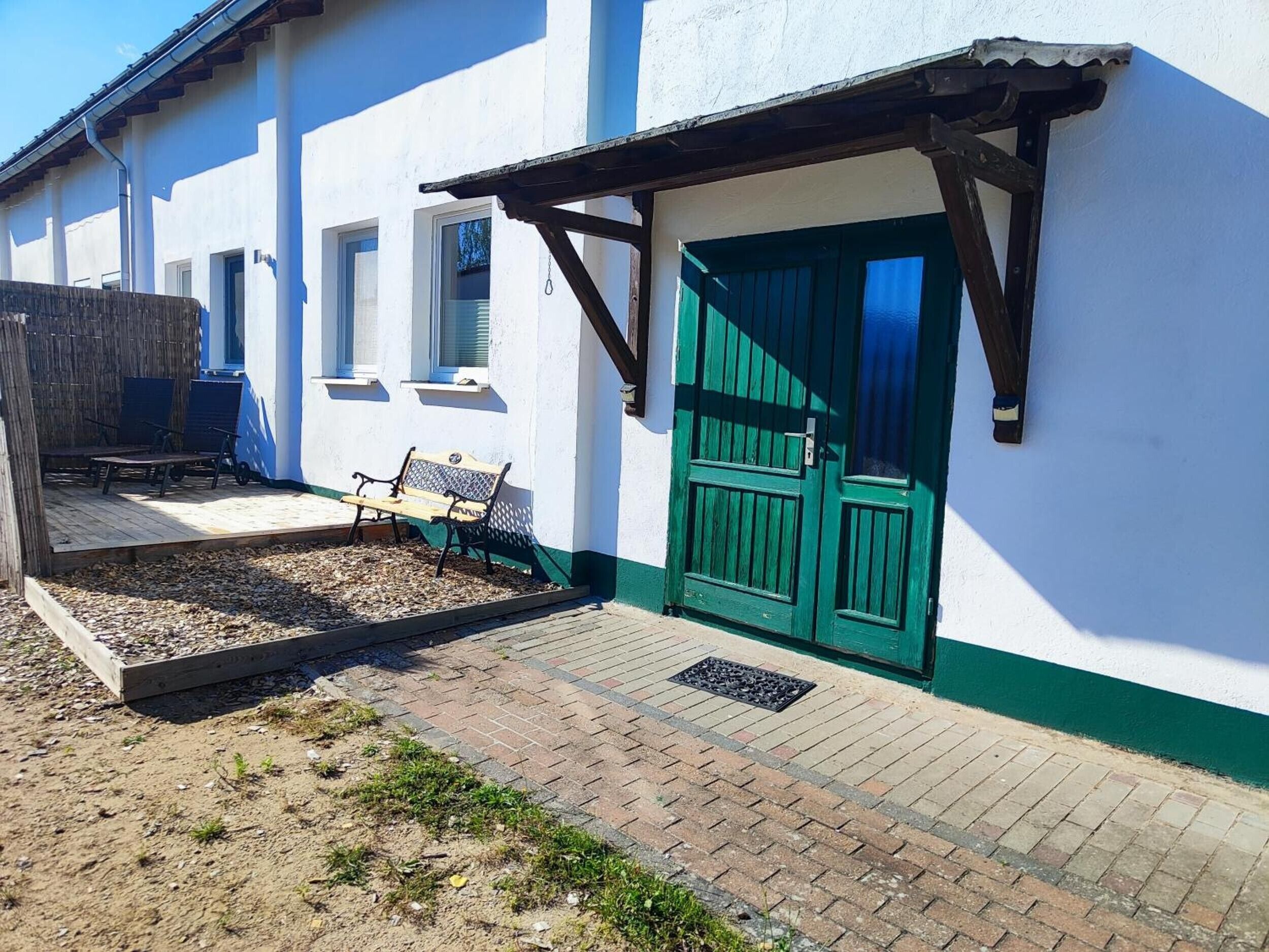 A building with a green door, a bench, and a wooden structure.