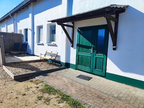 Un edificio con una porta verde, una panchina e una struttura in legno.