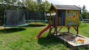 Une aire de jeux avec un toboggan, un trampoline et une maison de jeu colorée.
