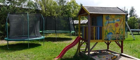 Une aire de jeux avec un toboggan, un trampoline et une maison de jeu colorée.