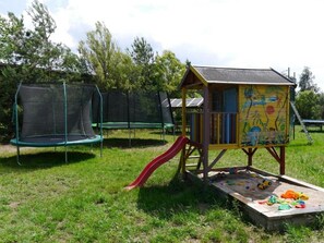 A playground with a slide, trampoline, and a colorful playhouse.