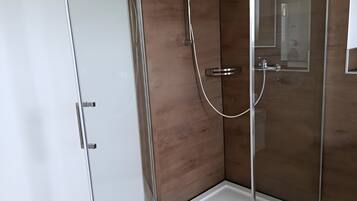 Une douche entièrementClose avec des parois en verre, un mur en bois et un sol blanc.