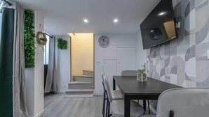 A modern dining area with a table, chairs, and a flat-screen TV mounted on the wall. - Apartment Cosy - 2BR/6P - Near Montorgueil (Paris)
