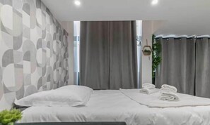 A modern hotel room with a large bed, a geometric patterned wall, and a view of the outdoors. - Apartment Cosy - 2BR/6P - Near Montorgueil (Paris)