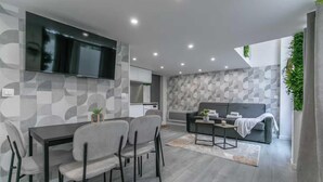 A modern living space with a dining area, a sofa, and a TV mounted on the wall. - Apartment Cosy - 2BR/6P - Near Montorgueil (Paris)
