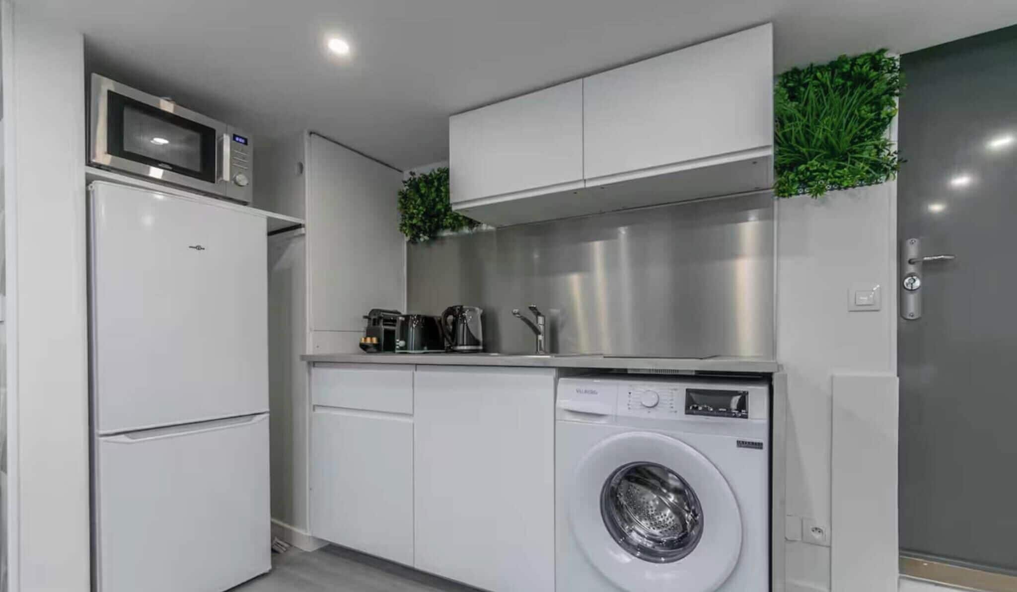 A compact kitchen with a built-in washing machine, a microwave, and a coffee maker.