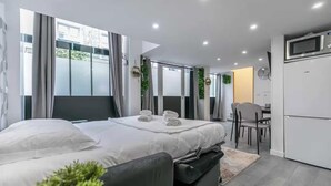 A modern hotel room with a bed, a desk, and a kitchenette. - Apartment Cosy - 2BR/6P - Near Montorgueil (Paris)