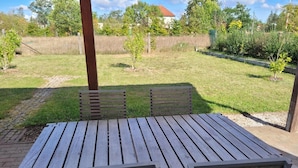 An outdoor wooden table with benches, surrounded by a grassy area and trees.